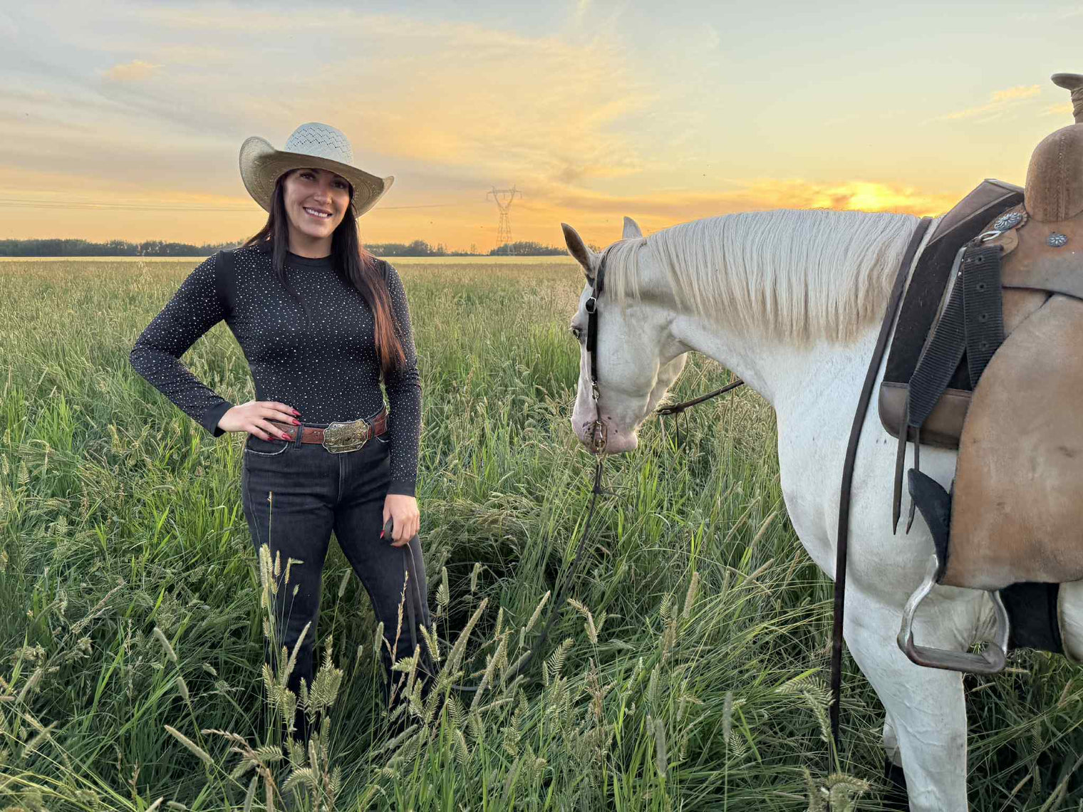 Woman in a cowboy hat wearing a black bodysuit that matches her horse's black Alliance Equine V20x hhorse boots and bell boots.
